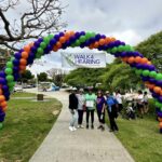 People standing at the Walk4Hearing balloon arch display